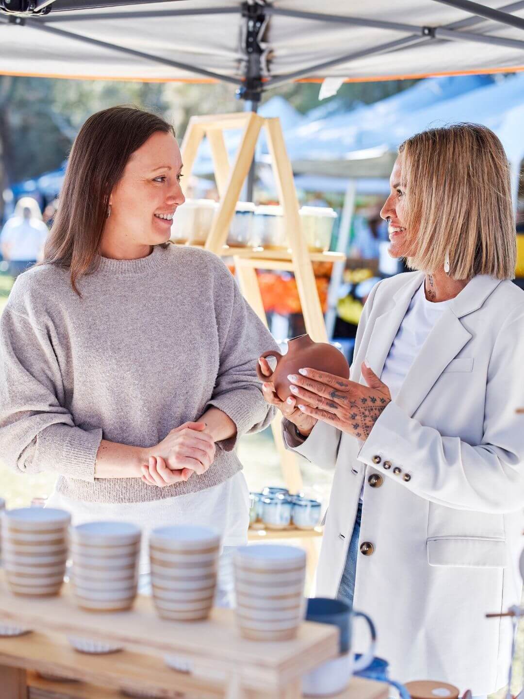 Two women looking at handmade pottery at a market stall